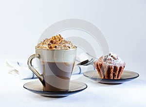 Coffee, cappuccino with whipped cream sprinkled with nuts, ground chocolate and cinnamon. Chocolate muffin in icing sugar.