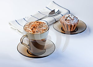 Coffee, cappuccino with whipped cream sprinkled with nuts, ground chocolate and cinnamon. Chocolate muffin in icing sugar.