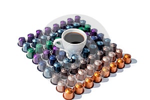 Coffee capsules different colors and white cup of hot black coffee on white background isolated