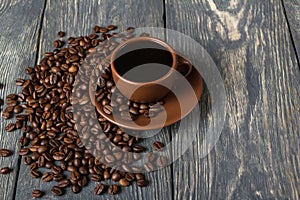 Coffee in ceramic Cup, coffee beans scattered near, on wooden table