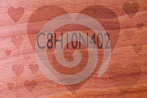 Coffee chemical formula C8H10N4O2 with hearts on a wooden background. Coffee love concept