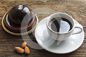 Coffee with chocolate cake and almonds on wood background