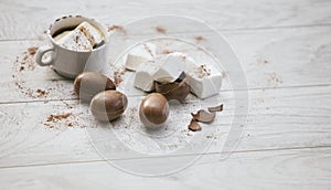 Coffee or chocolate in a white mug with marshmallows and chocolate eggs