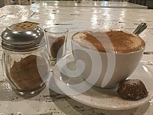 coffee with cinnamon powder and cookie . Cappuccino.