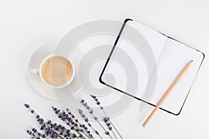 Coffee, clean notebook and lavender flower on white table from above. Woman working desk. Cozy breakfast. Mockup. Flat lay style.