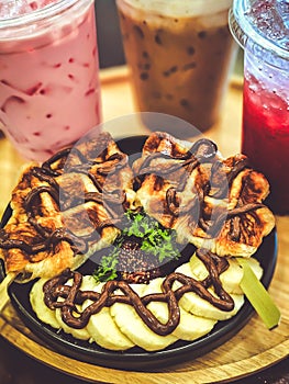 Coffee, cocoa and syrup served with waffles topped with chocolate and fresh strawberries