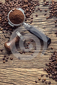 Coffee.Coffee beans and portafilter on old oak wooden table