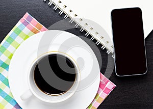 Coffee on colorful cloth with blank smart phone display.