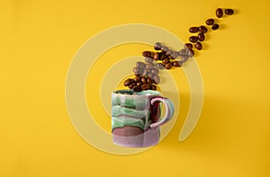 Coffee Concept. Creativity and Energetic. Rustic Cup with Roasted beans arranged as Coffee Splash on Yellow background