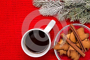 Coffee, cookies with cinnamon and fir tree branch on knitted background