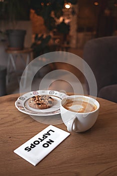 Coffee and cookies on a wooden table with a sign saying \