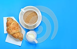 Coffee and croissant on a blue background. French breakfast
