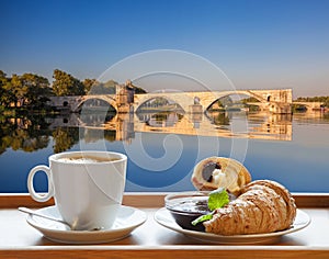 Coffee with croissants against Avignon old bridge in Provence, France