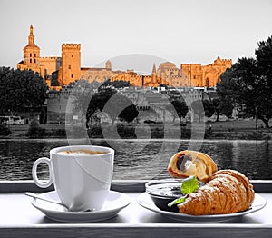 Coffee with croissants against Avignon town in Provence, France photo