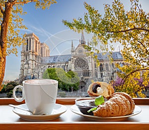 Coffee with croissants against cathedral Notre Dame in Paris, France