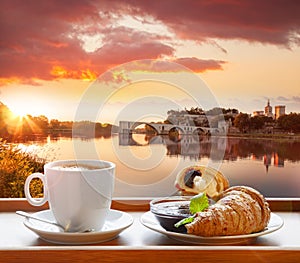 Coffee with croissants against Avignon old bridge in Provence, France