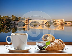 Coffee with croissants against Avignon old bridge in Provence, France photo
