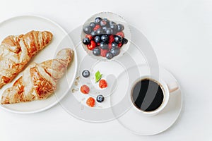 Coffee, croissants and berries breakfast on a white table. Top view, flat lay