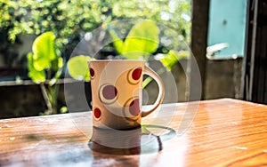Coffee Cup backlit by Morning Sunlight. Dining Table top shot. Front view`. Tea cup placed on tea party table at sidewalk cafe.