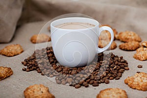 coffee cup with beans and cookies. Cappuccino white mug, coffee beans, sweets on the background