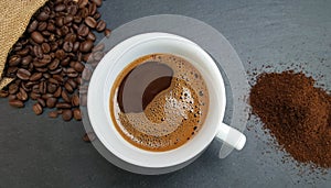 Coffee cup, beans and ground powder on dark background