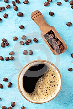 Coffee cup and beans in a scoop, shot from above on a blue background