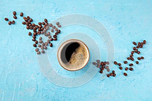 Coffee cup and beans, top shot on a blue background with copy space
