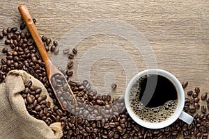 Coffee cup with beans, wood spoon and hemp sack bag on wood table