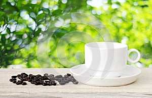 Coffee cup and beans on wood table over blurred tree background