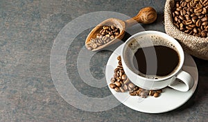 Coffee cup and beans with wooden shovel or spoon and stack of beans in burlap sack, on black rustic vintage table, Coffee concept