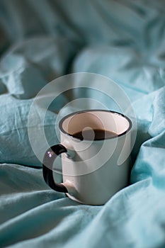 Coffee cup on a bed. Atmospheric hygge style. Good morning still life