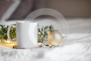 Coffee cup on a beige knited background with eucaliptus leaves and christmas garland lights