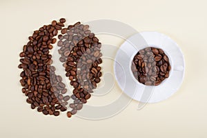 Coffee cup and big coffee bean made of scattered beans.