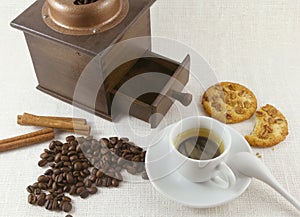 Coffee cup, biscuit, grinder and coffeebeans on table