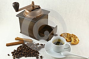 Coffee cup, biscuit, grinder and coffeebeans on table