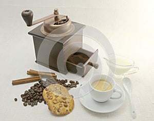 Coffee cup, biscuit, grinder and coffeebeans on table