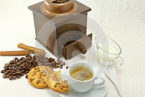 Coffee cup, biscuit, grinder and coffeebeans on table