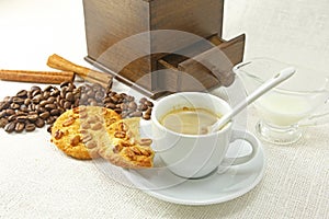 Coffee cup, biscuit, grinder and coffeebeans on table