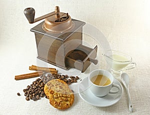 Coffee cup, biscuit, grinder and coffeebeans on table