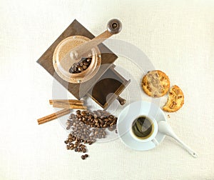 Coffee cup, biscuit, grinder and coffeebeans on table