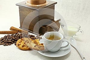 Coffee cup, biscuit, grinder and coffeebeans on table