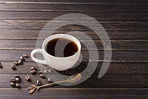 Coffee cup with black coffee and coffee beans on wooden table background, top view