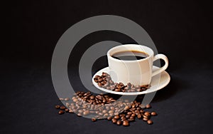Coffee cup with black coffee on dark background. Roasted coffe beans near.