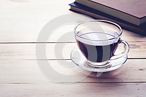 Coffee cup with book on wood table in morning