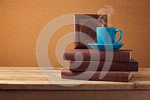 Coffee cup and books on wooden vintage table over retro background