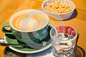 Coffee in a cup and bowl of nuts on a table