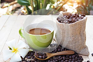 Coffee cup with burlap sack of coffee beans on wooden table