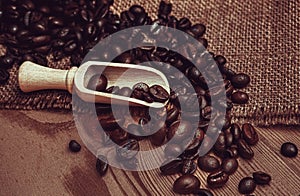 Coffee cup with burlap sack of roasted beans on brown old wooden table