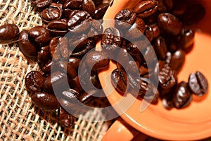 Coffee cup with burlap sack of roasted beans on rustic table