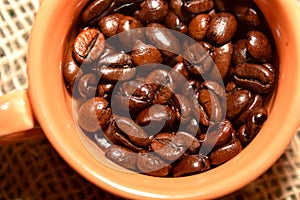 Coffee cup with burlap sack of roasted beans on rustic table